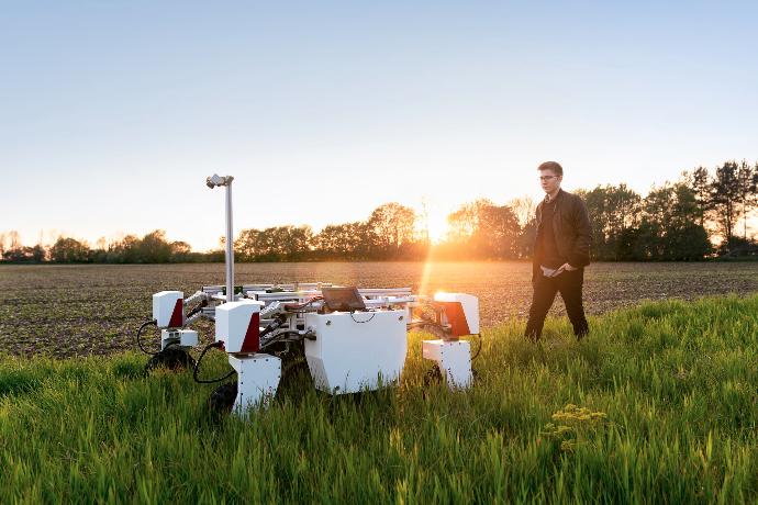 man in brown shirt standing on green grass field during sunset